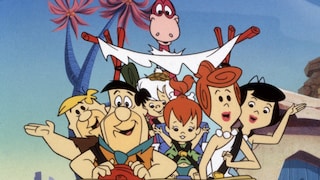 Zeichentrickszene aus „The Flintstones“: Mehrere Figuren sitzen gemeinsam in einem offenen Steinzeitfahrzeug. Vorne sind zwei Figuren am Steuer und auf dem Beifahrersitz zu sehen, dahinter weitere Figuren sowie ein kleines Kind. Über dem Fahrzeug ragt ein rosafarbenes Dino-Tier mit langem Hals hervor. Das Auto besitzt ein Dach aus Holzstangen und weißem Stoff. Im Hintergrund stehen stilisierte Bäume mit violett-blauen Stämmen und rosafarbenen Blättern vor einem hellblauen Himmel.