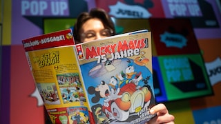 Eine Person liest die Jubiläumsausgabe des Micky-Maus-Magazins