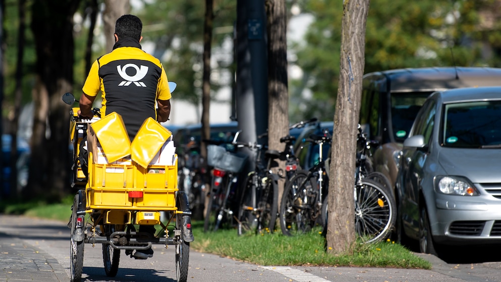 Ein Briefträger fäht mit seinem Fahrrad eine Straße in München entlang