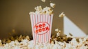Popcorn-Becher umringt von ganz viel Popcorn