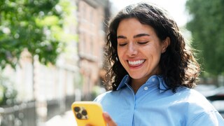 Frau lächelt und schaut auf ihr Smartphone