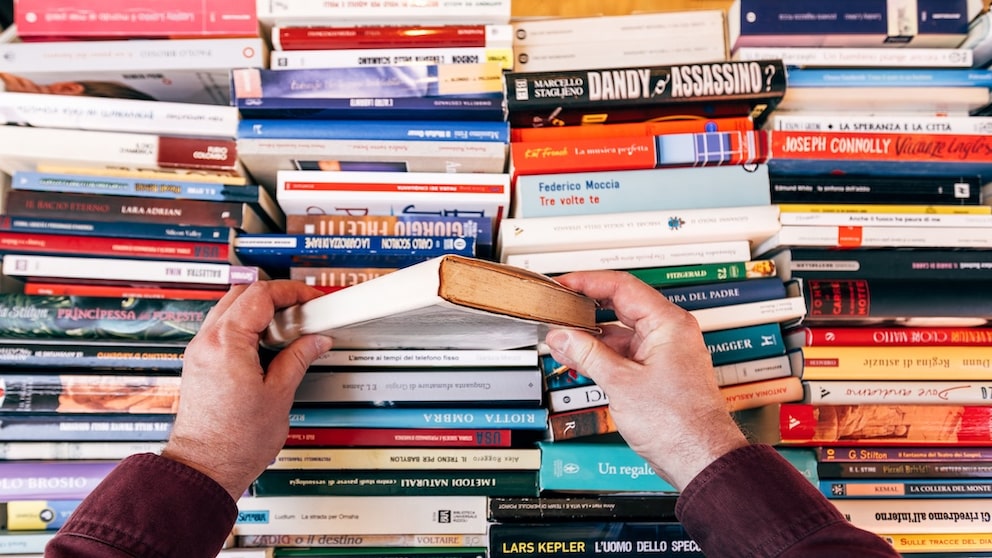 Person wühlt sich durch mehrere Bücher