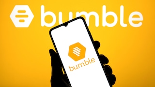Vor gelbem Hintergrund ist groß das weiße Bumble-Logo zu sehen. Im Vordergrund hält eine Hand ein Smartphone, auf dessen hellem Display ebenfalls das Bumble-Logo abgebildet ist.