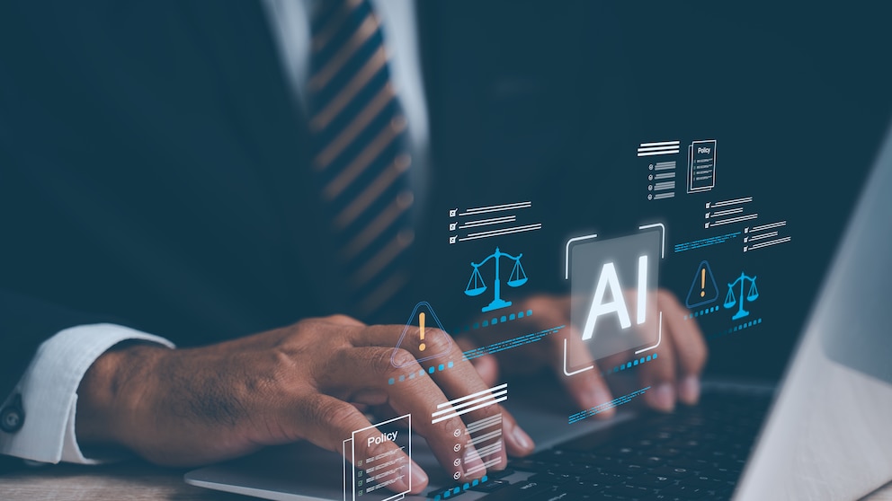 Ein Mann in Anzug sitzt an einem Schreibtisch und arbeitet mithilfe von AI auf seinem Laptop.