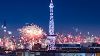 Der Berliner Funkturm in der Skyline Berlins bei Nacht umgeben von Feuerwerk