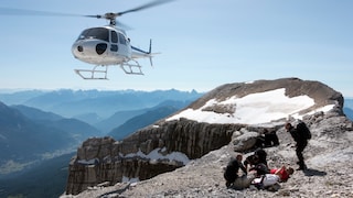 Hubschrauber der Bregrettung über einer Gruppe Bergsteiger