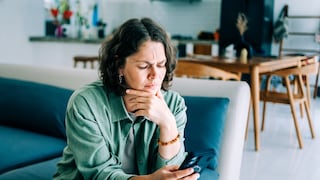 Frau mit iPhone auf Sofa