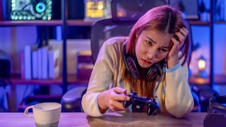 Gamerin sitzt enttäuscht mit einem Controller in der Hand am Schreibtisch