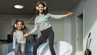 Zwei Mädchen tanzen zu Musik auf dem Bett