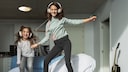Zwei M&auml;dchen tanzen zu Musik auf dem Bett