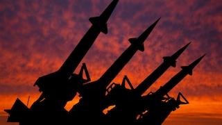 Silhouette von waffenfähigen Raketen vor einem durch den Sonnenuntergang getränkten rotem Himmel