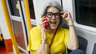 Frau telefoniert in der Bahn und berührt dabei ihre Brille