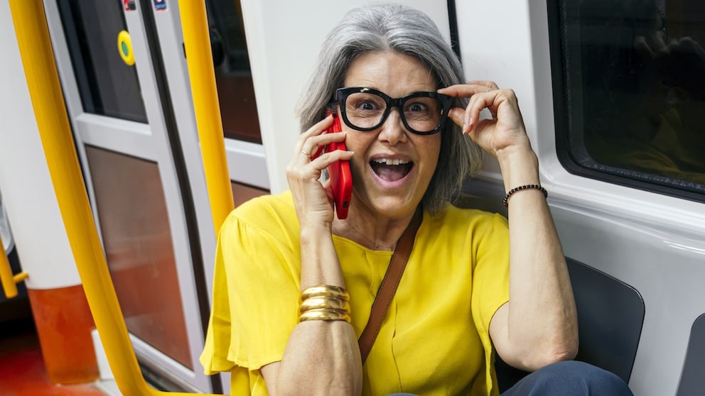 Frau telefoniert in der Bahn und berührt dabei ihre Brille