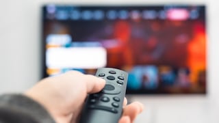 Person zeigt mit der Fernbedienung auf einen Fernseher