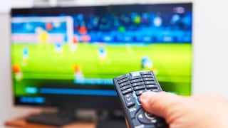 Person zeigt mit der Fernbedienung auf einen TV