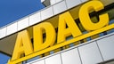 Gro&szlig;e gelbe ADAC-Buchstaben an der Fassade eines modernen Geb&auml;udes. Die Aufnahme zeigt das Logo schr&auml;g von unten vor blauem Himmel. Die Geb&auml;udefassade besteht aus hellen Metall- und Glaselementen.