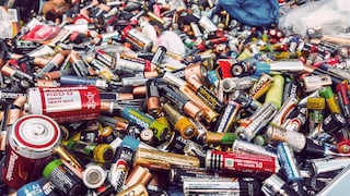 Großer Haufen aus gebrauchten Batterien verschiedener Größen und Marken. Zu sehen sind zahlreiche AA-, AAA-, C- und D-Zellen sowie weitere Batterietypen in unterschiedlichen Farben, die ungeordnet übereinanderliegen. Einige Batterien zeigen Gebrauchsspuren und Korrosion. Im Hintergrund befinden sich weitere Batterien und Kunststoffsäcke.