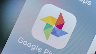 Nahaufnahme des Google-Fotos-App-Symbols auf dem Display eines Smartphones. Unter dem bunten Logo ist der Schriftzug „Google Photos“ zu sehen.