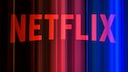 Abstraktes Bild des roten Netflix-Schriftzugs vor einem dunklen Hintergrund mit vertikalen Lichtstreifen in Rot, Pink und Blau.