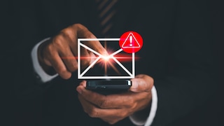 Person hält ein Smartphone in der Hand und tippt auf ein eingeblendetes Briefumschlag-Symbol. Daneben ist ein rotes Warnsymbol mit Ausrufezeichen zu sehen. Das Bild visualisiert eine verdächtige oder potenziell gefährliche E-Mail.