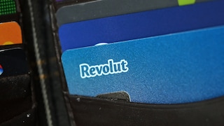 Mehrere Bank- und Zahlungskarten stecken in einem schwarzen Kartenfach. Im Vordergrund ist eine blaue Revolut-Karte mit weißem Revolut-Logo zu sehen. Dahinter ragen weitere Karten in verschiedenen Farben hervor.
