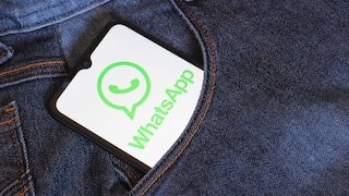 Ein Smartphone mit geöffnetem WhatsApp-Logo steckt in der Tasche einer blauen Jeans.