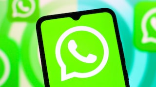 Ein Smartphone mit groß dargestelltem WhatsApp-Logo steht im Vordergrund. Auf dem Bildschirm ist das weiße WhatsApp-Symbol auf grünem Hintergrund zu sehen. Im unscharfen Hintergrund erscheinen weitere vergrößerte WhatsApp-Logos in Grün und Weiß.
