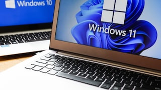 Zwei aufgeklappte Laptops stehen nebeneinander auf einem Tisch. Auf dem Bildschirm im Vordergrund ist das Windows-11-Logo mit blauem Hintergrund zu sehen. Im Hintergrund zeigt ein weiterer Bildschirm den Schriftzug Windows 10 auf blauem Hintergrund. Beide Geräte sind leicht versetzt zueinander aufgenommen.