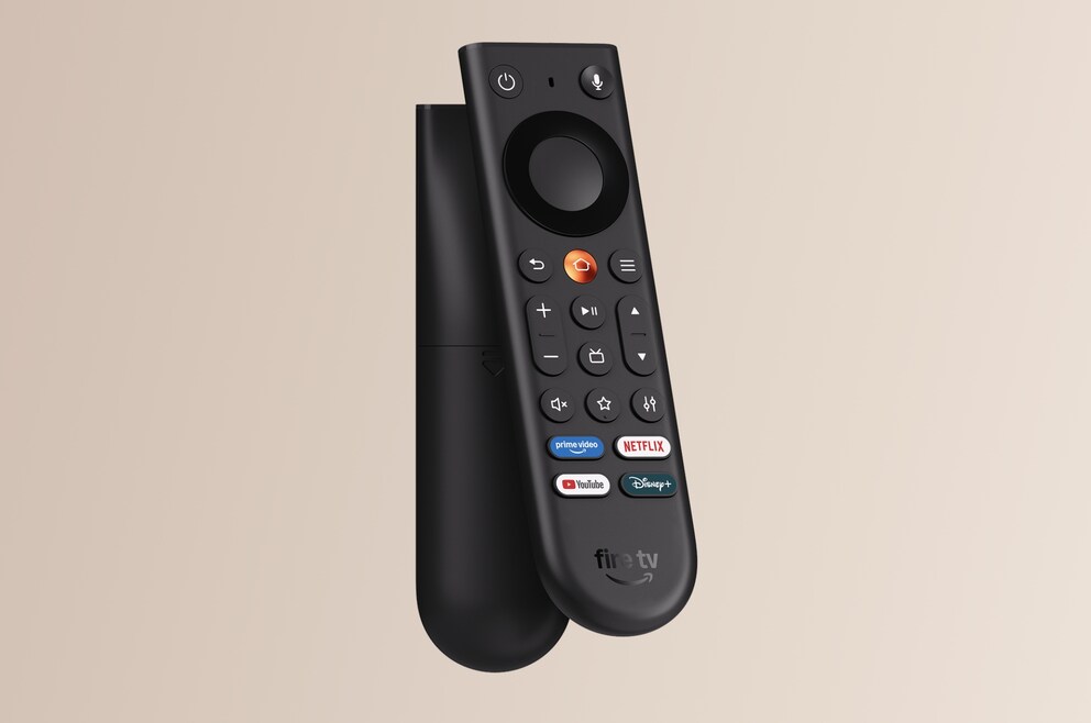 A black Amazon Fire TV remote leans against a black Fire TV Stick. The remote features a large control pad, volume buttons, function buttons, and quick access buttons for Prime Video, Netflix, YouTube, and Disney+. Both devices are shown against a solid, light beige background. The remote stands slightly angled in front of the streaming stick, partially covering it.