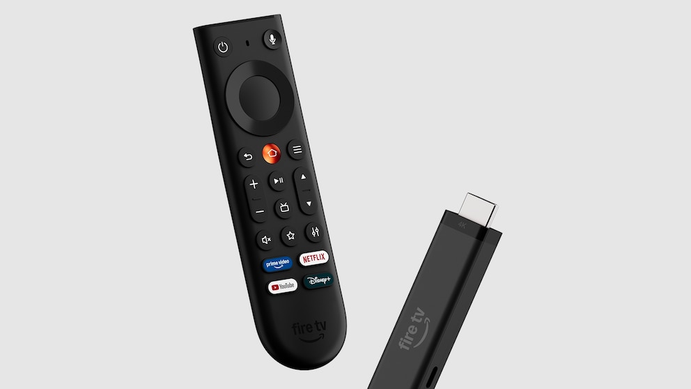 Vor grauem Hintergrund sind ein Amazon Fire TV Stick und die dazugehörige Fernbedienung freigestellt dargestellt. Die schwarze Fernbedienung zeigt ein Steuerkreuz, Lautstärketasten, mehrere Funktionstasten sowie Schnellzugriffe für Prime Video, Netflix, YouTube und Disney+. Daneben ist der schwarze Fire TV Stick mit HDMI-Anschluss und dem Aufdruck „fire tv“ zu sehen. Beide Geräte sind leicht schräg ausgerichtet und scheinen vor dem Hintergrund zu schweben.