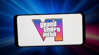 Ein Smartphone liegt quer vor einem blau und pink leuchtenden Hintergrund. Auf dem weißen Display ist das Logo von "Grand Theft Auto VI" zu sehen. Hinter dem Schriftzug steht eine große römische Sechs mit einem Farbverlauf von Blau über Pink bis Orange.