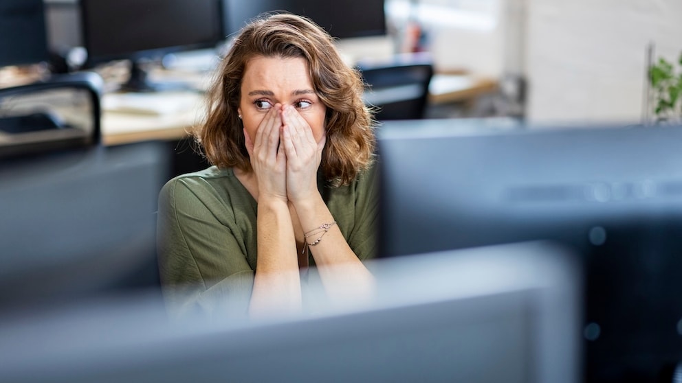 Frau sitzt vor einem Monitor und schaut erschrocken