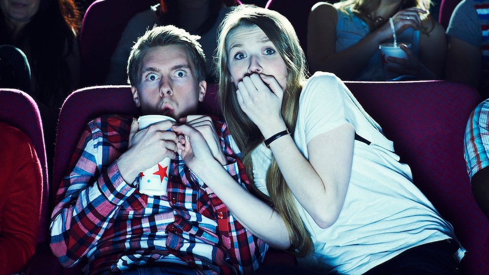 Paar sitzt im Kino und schaut einen furchterregenden Film