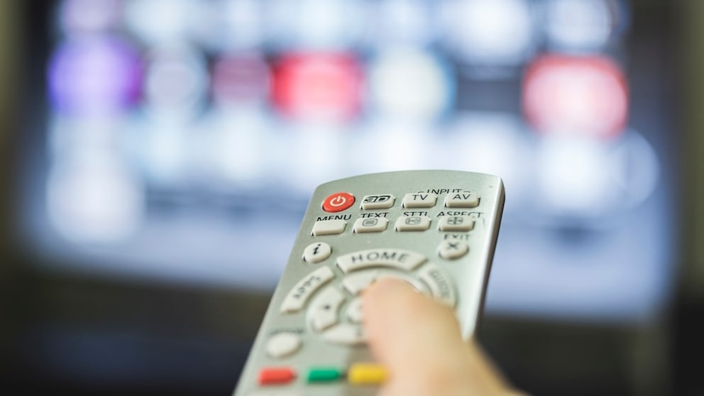 Person zeigt mit der Fernbedienung auf einen Fernseher