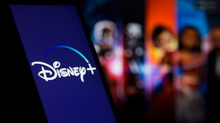 Ein Smartphone mit leuchtendem Disney-Plus-Logo vor einem unscharfen, farbenfrohen Hintergrund mit Personen und Bildschirmen.