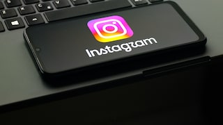 Auf einem Smartphone ist das Instagram-Logo zu sehen, das Gerät liegt auf der Tastatur eines Laptops