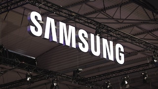 Großes beleuchtetes Samsung-Logo unter einer Hallendecke mit Metallträgern und Veranstaltungstechnik