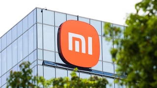 Xiaomi-Logo an der Glasfassade eines modernen Gebäudes, teilweise von grünen Bäumen eingerahmt