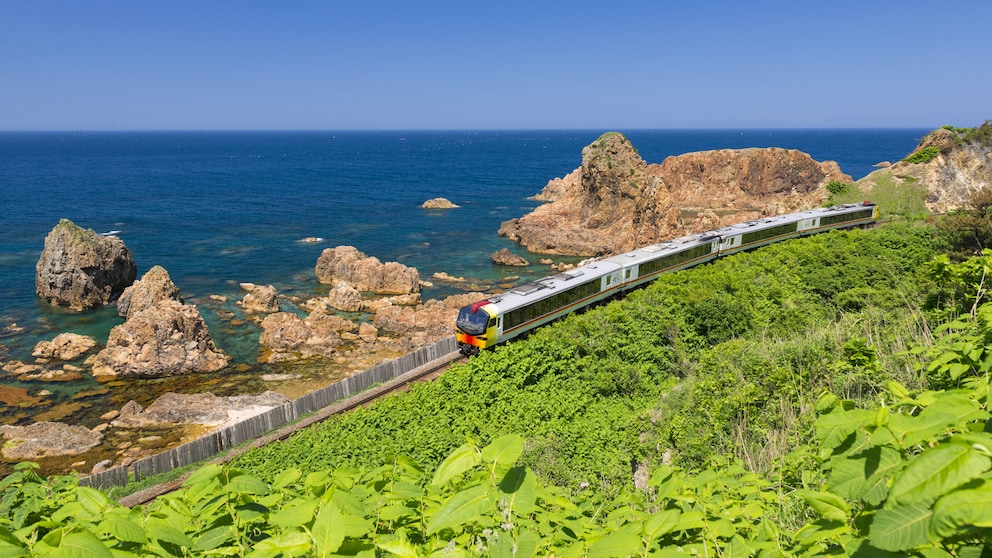 Rund um die Welt gibt es atemberaubende Bahnstrecken. Im Bild zu sehen: Ein Zug der Gonō Line in Japan, der im Norden des Landes an der Küste entlangfährt.