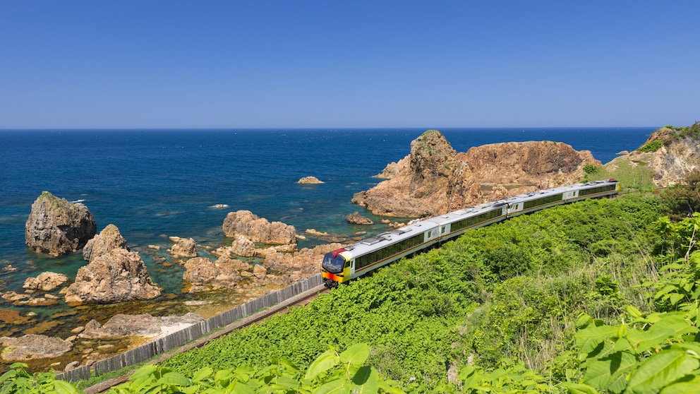 Rund um die Welt gibt es atemberaubende Bahnstrecken. Im Bild zu sehen: Ein Zug der Gonō Line in Japan, der im Norden des Landes an der Küste entlangfährt.