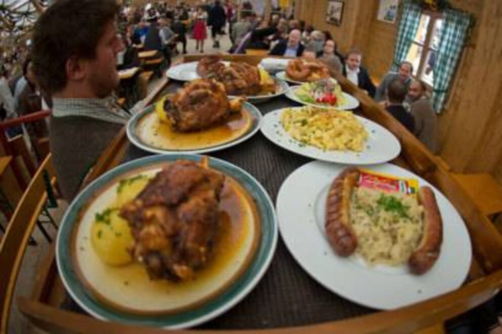 Auf dem Oktoberfest werden Unmengen an Tellern mit bayrischen Spezialitäten an die Gäste verteilt