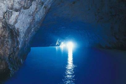 Durch einen kleinen Eingang fällt Licht in die berühmte Blaue Grotte von Capri. Es wird schnell ersichtlich, woher der Name der Meereshöhle kommt.