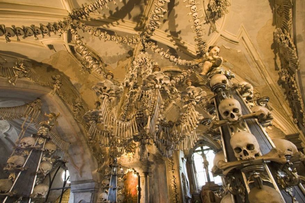 Als die kleine Kirche in Sedlec (Sedletz), einem verträumten Vorort des Touristenmagneten Kutná Hora (Kuttenberg), 1866 in den Besitz der Familie von Schwarzenbergs kam, lagerten sechs riesige Pyramiden aus Menschenknochen in der Kapelle – auf dem Friedhof war für diese kein Platz mehr gewesen. Die neuen Hausherren wollten die Kirche nicht mehr als solche nutzen, aber schön sollte sie sein. Also beauftragten sie den Holzschnitzer Frantièek Rint damit, das Interieur neu zu gestalten – mit dem Material, das er dort vorfand. Rint machte sich an die Arbeit, schmückte den Altar mit Schädeln, bastelte Girlanden aus Knochen, Kruzifixe aus Schenkelknochen, Kerzenhalter aus Totenköpfen – und schuf so die heutige, an Morbidität kaum zu übertreffende „Kapelle der Geister“. Die Top-Sehenswürdigkeiten in Tschechien