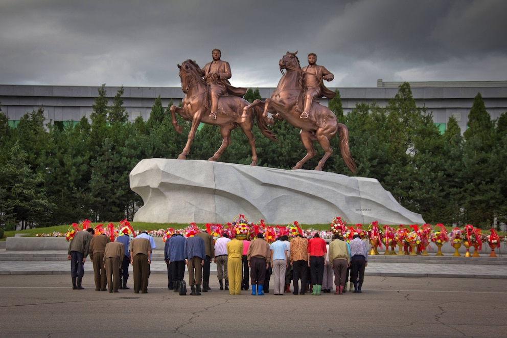 Koreaner vor zwei Statuen in Pjöngjang, die Staatsgründer Kim Il-sung und seinen Sohn Kim Jong-il zeigen