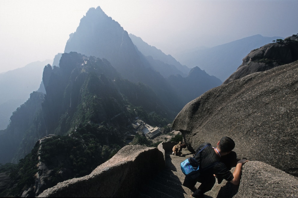 Nervenkitzel, wohin man geht und schaut: Der abschüssige Weg im Huangshan-Gebirge führt über steinerne Stufen zum 1864 Meter hohen Lotusblütengipfel, dem höchsten von insgesamt 72 Gipfeln in den „Gelben Bergen“ (links)