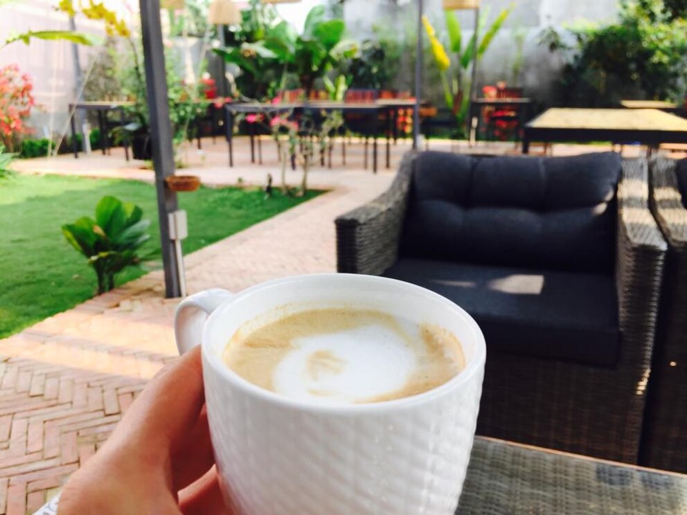 Digital Nomads: Kaffeetasse mit Cappuccino, im Hintergrund Gartenmöbel