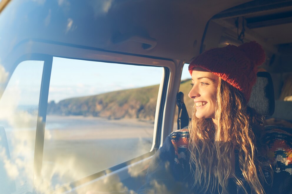 Frau guckt aus dem Auto auf den Strand