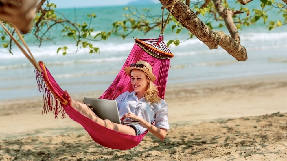 Digital Nomads: Frau liegt in Hängematte mit LapTop