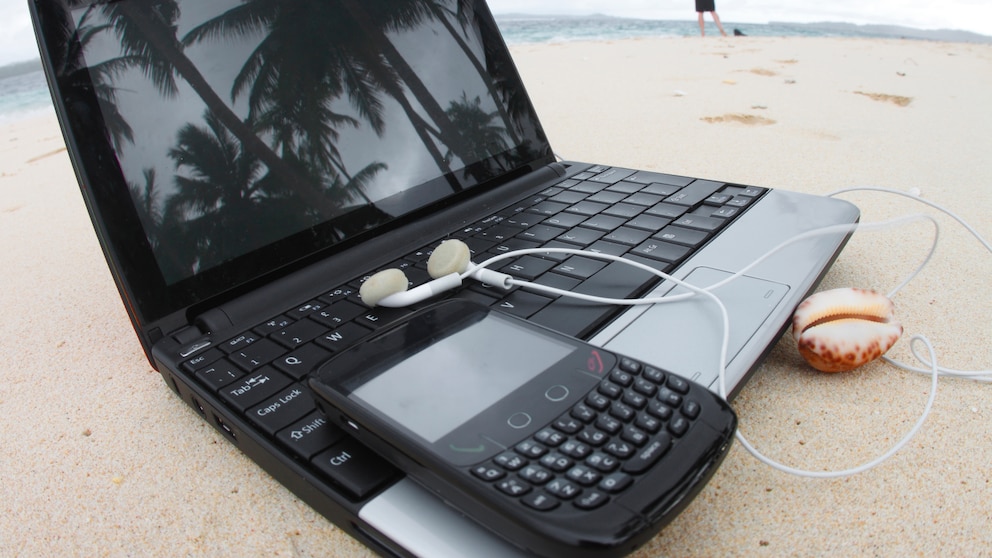 Laptop und Handy am Strand