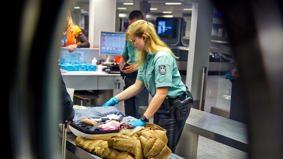 Eine Zoll-Mitarbeiterin kontrolliert am Flughafen einen Koffer auf Gegenstände, die möglicherweise versteuert werden müssen